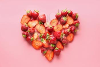 Heart made of red strawberry on color background�