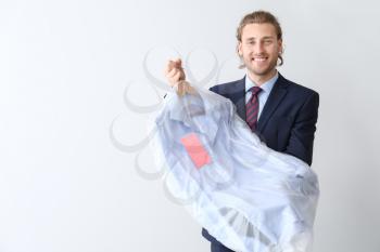 Businessman with clothes after dry-cleaning on white background�