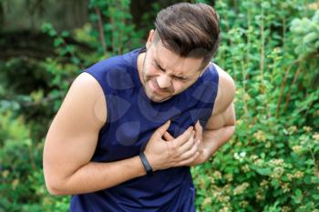 Sporty young man suffering from heart attack outdoors�