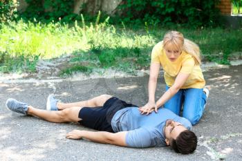 Woman giving CPR to unconscious man outdoors�