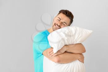 Handsome man hugging pillow against white background�