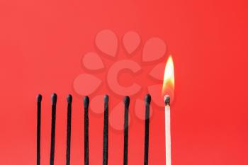 One burning match among burnt-out ones on color background. Concept of uniqueness�