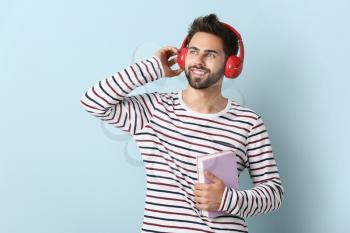 Young man listening to audiobook on light background�