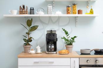Modern coffee machine, cups and croissants on kitchen table�