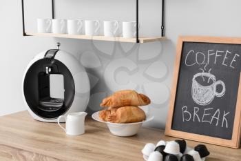 Modern coffee machine and croissants on kitchen table�