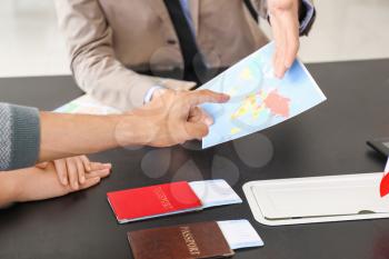 Male travel agent working with young couple in office�