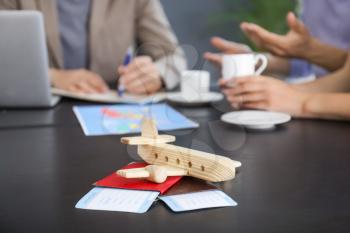 Wooden airplane with passports and tickets on table in travel agency�