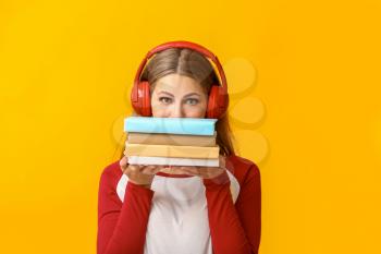 Young woman listening to audiobook on color background�