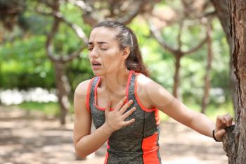 Sporty young woman suffering from heart attack outdoors�