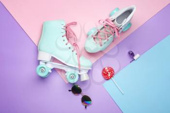 Vintage roller skates and accessories on color background�