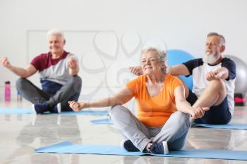 Elderly people practicing yoga in gym�