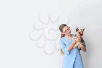 Veterinarian with cute dog on light background�