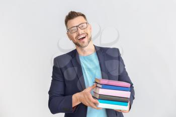 Handsome male teacher with books on light background�