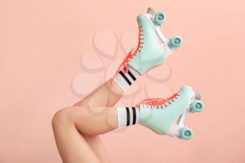 Legs of woman in vintage roller skates on color background�