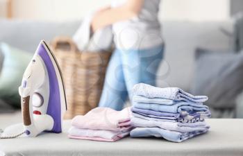 Stacks of clean clothes on ironing board at home�