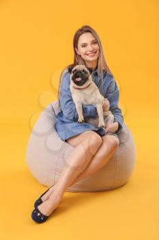 Beautiful young woman with cute pug dog on color background 
