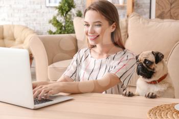 Beautiful young woman with cute pug dog working on laptop at home�