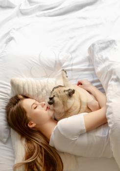Morning of beautiful young woman with cute pug dog in bedroom�