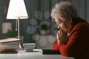 Senior woman praying to God at night�