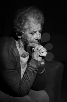 Black and white portrait of praying senior woman�