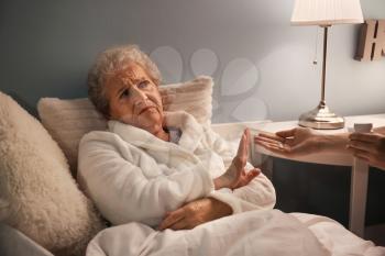 Senior woman refusing to take medicine against insomnia at night�