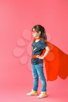 Cute little girl dressed as superhero on color background�