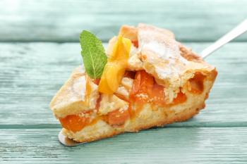 Piece of tasty peach pie on wooden background, closeup�