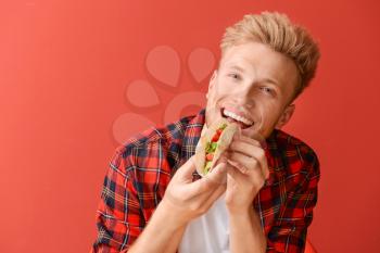 Man eating tasty taco on color background�