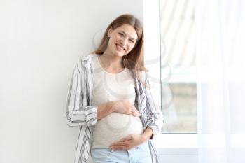 Beautiful pregnant woman near window�