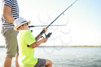 Father and son fishing together on river�