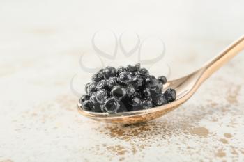 Spoon with black caviar on white background�
