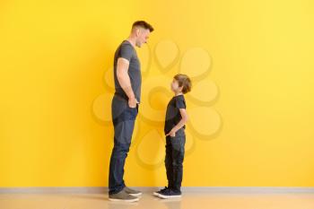 Portrait of father and son near color wall�