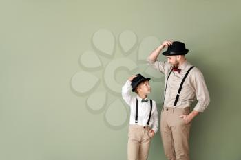 Portrait of fashionable father and son on color background�