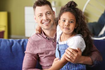 Happy man with little adopted African-American girl at home�