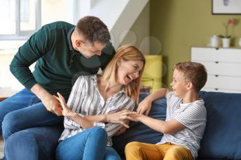 Happy couple playing with little adopted child at home�