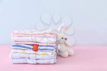 Stack of baby clothes on color background�