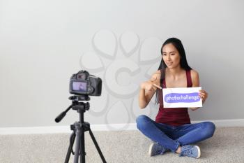 Female Asian blogger recording video near light wall�