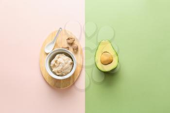 Bowl with shea butter and avocado on color background�