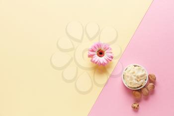 Shea butter with nuts and flower on color background�