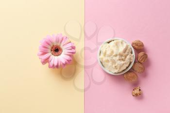 Shea butter with nuts and flower on color background�