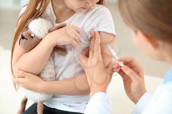 Doctor vaccinating little girl in clinic�