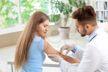 Doctor vaccinating young woman in clinic�
