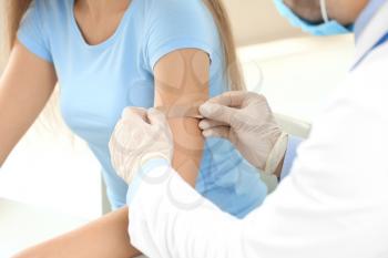 Doctor vaccinating young woman in clinic�