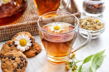 Cup of tasty chamomile tea with cookies on light table�