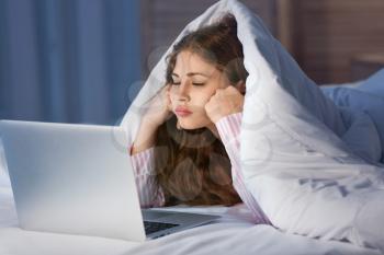 Teenage girl with laptop in bed at night�