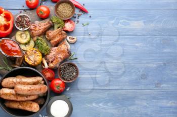 Tasty grilled meat with sausages and vegetables on wooden background�