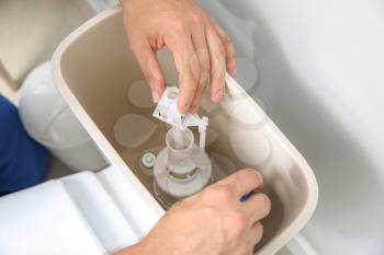 Plumber repairing toilet tank in restroom, closeup�