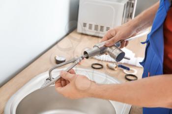Plumber installing sink in kitchen�