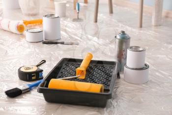 Paints with tray and supplies on floor in room�