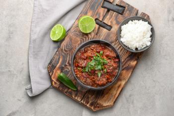 Bowls with tasty chili con carne and rice on grey background�